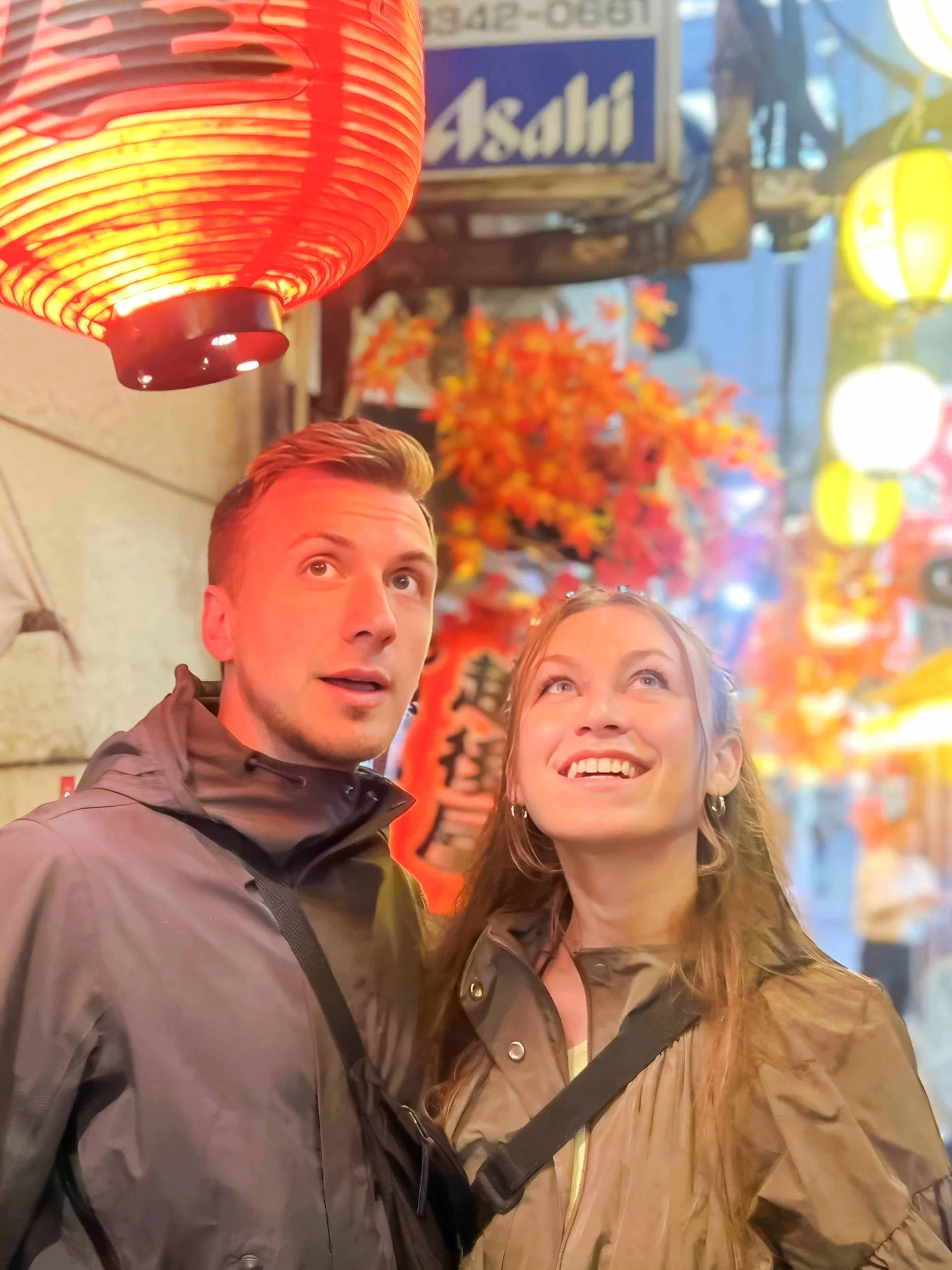 Couple admiring lanterns in Shinjuku alley during Tokyo food tour.