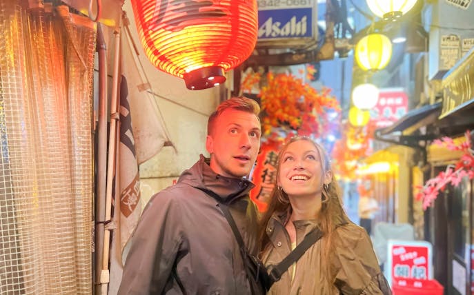 Couple admiring lanterns in Shinjuku alley during Tokyo food tour.