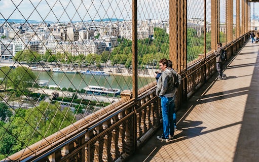 Visitors enjoying the view from the Eiffel Tower's second floor, overlooking the Seine River in Paris.