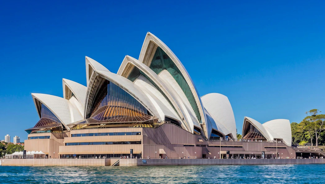 Sydney Opera House with iconic sail-like design against clear blue sky.
