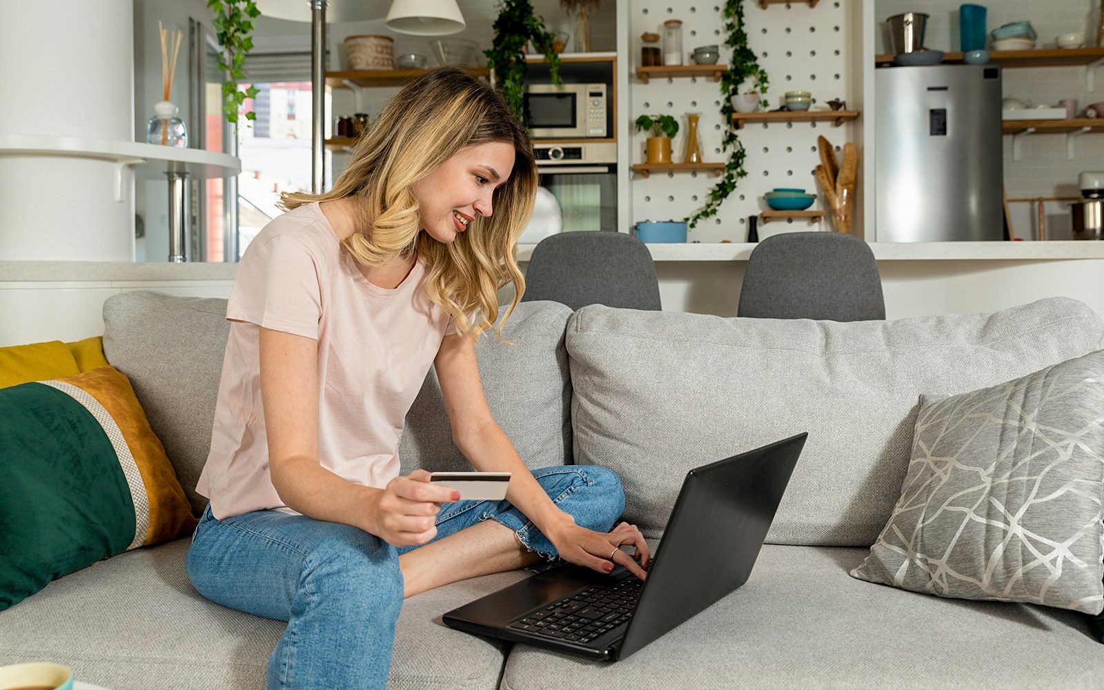 Person booking tickets online with a laptop and credit card at home.