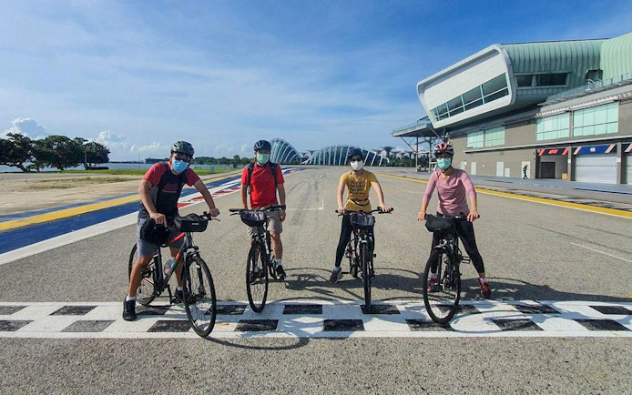 Cyclists on a track near modern architecture during Bike and Bites Food Tour.