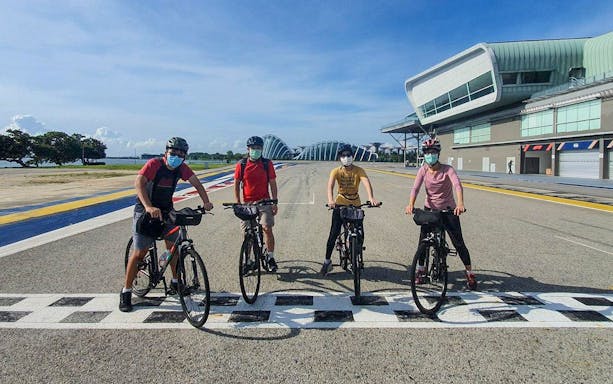 Cyclists on a track near modern architecture during Bike and Bites Food Tour.