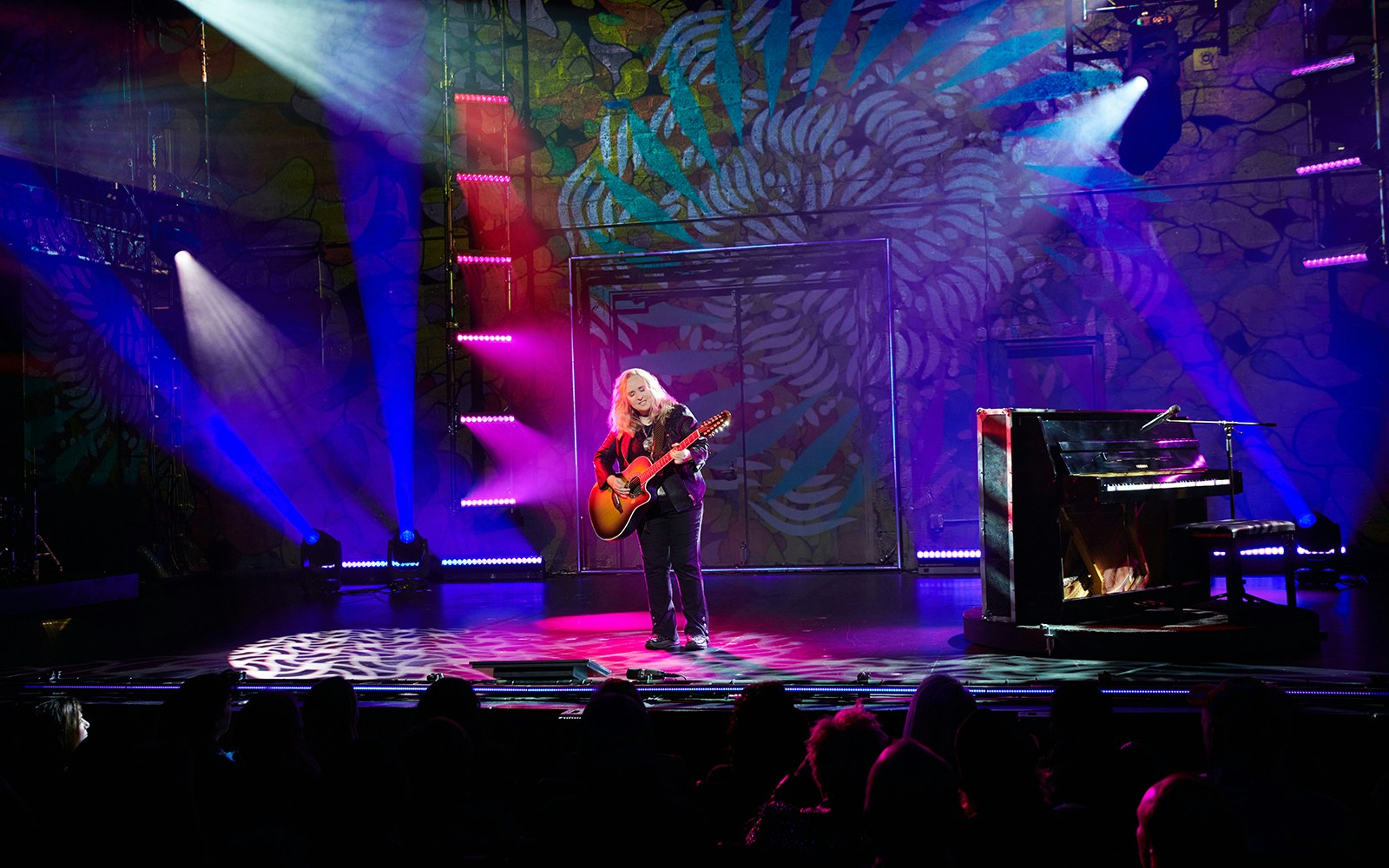 Musician performing on stage with guitar and piano during Melissa Etheridge: My Window show.