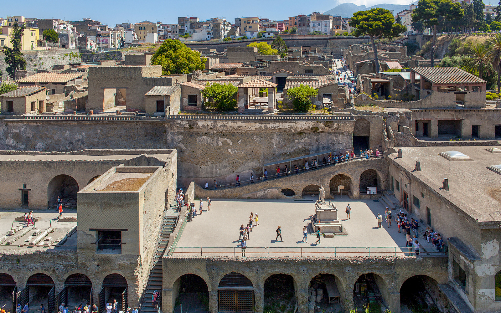 Visitors walking through the ancient ruins of Herculaneum basilica site.