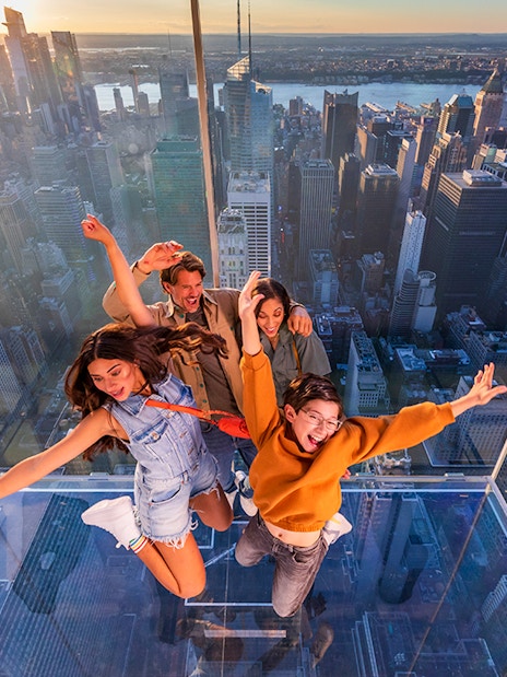 Group enjoying glass observation deck at SUMMIT One Vanderbilt, New York City skyline in background.