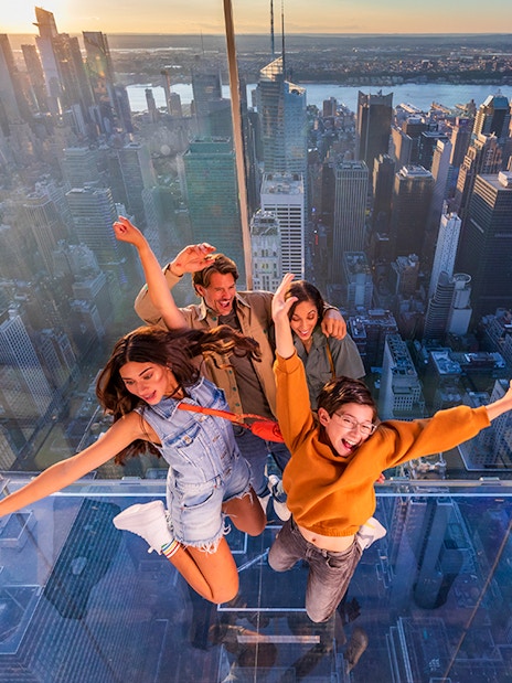 Group enjoying glass observation deck at SUMMIT One Vanderbilt, New York City skyline in background.