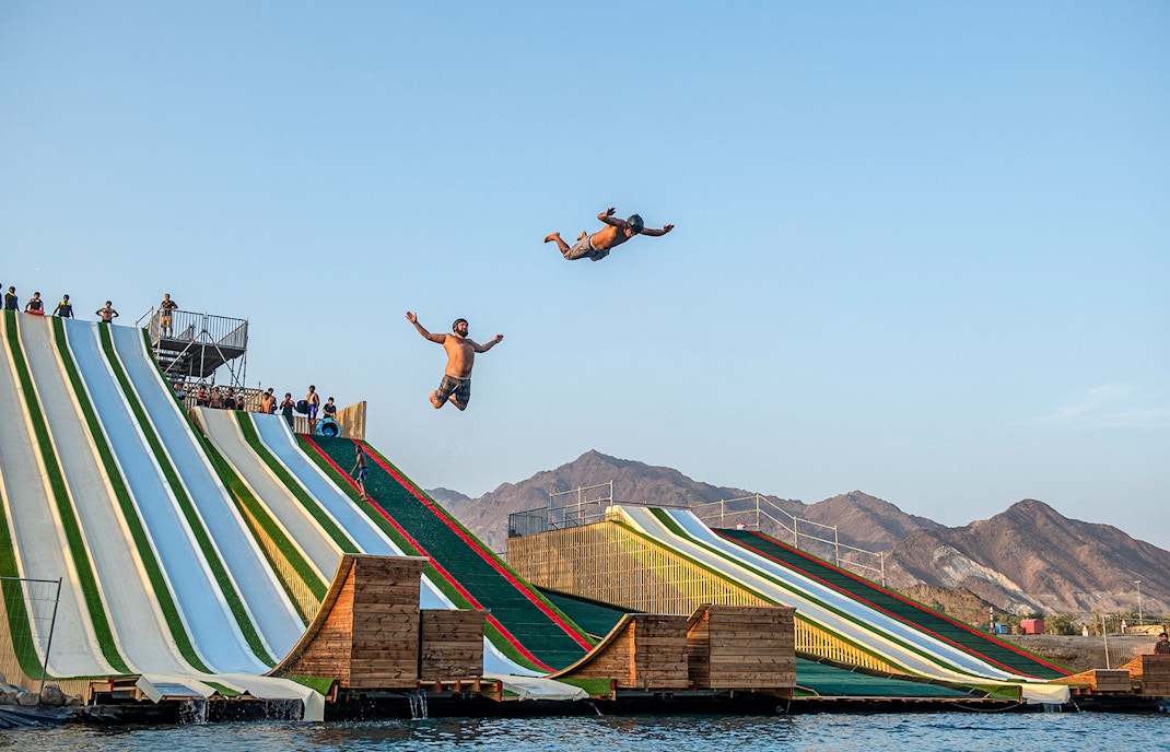 Visitors enjoying the slip 'n slide at Hatta Wadi Hub, Dubai, with tickets to Hatta Drop-in.