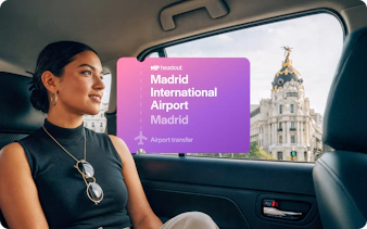 Passenger in car with view of Metropolis Building during Madrid airport transfer.