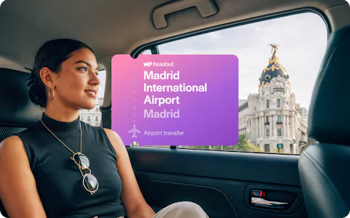 Passenger in car with view of Metropolis Building during Madrid airport transfer.