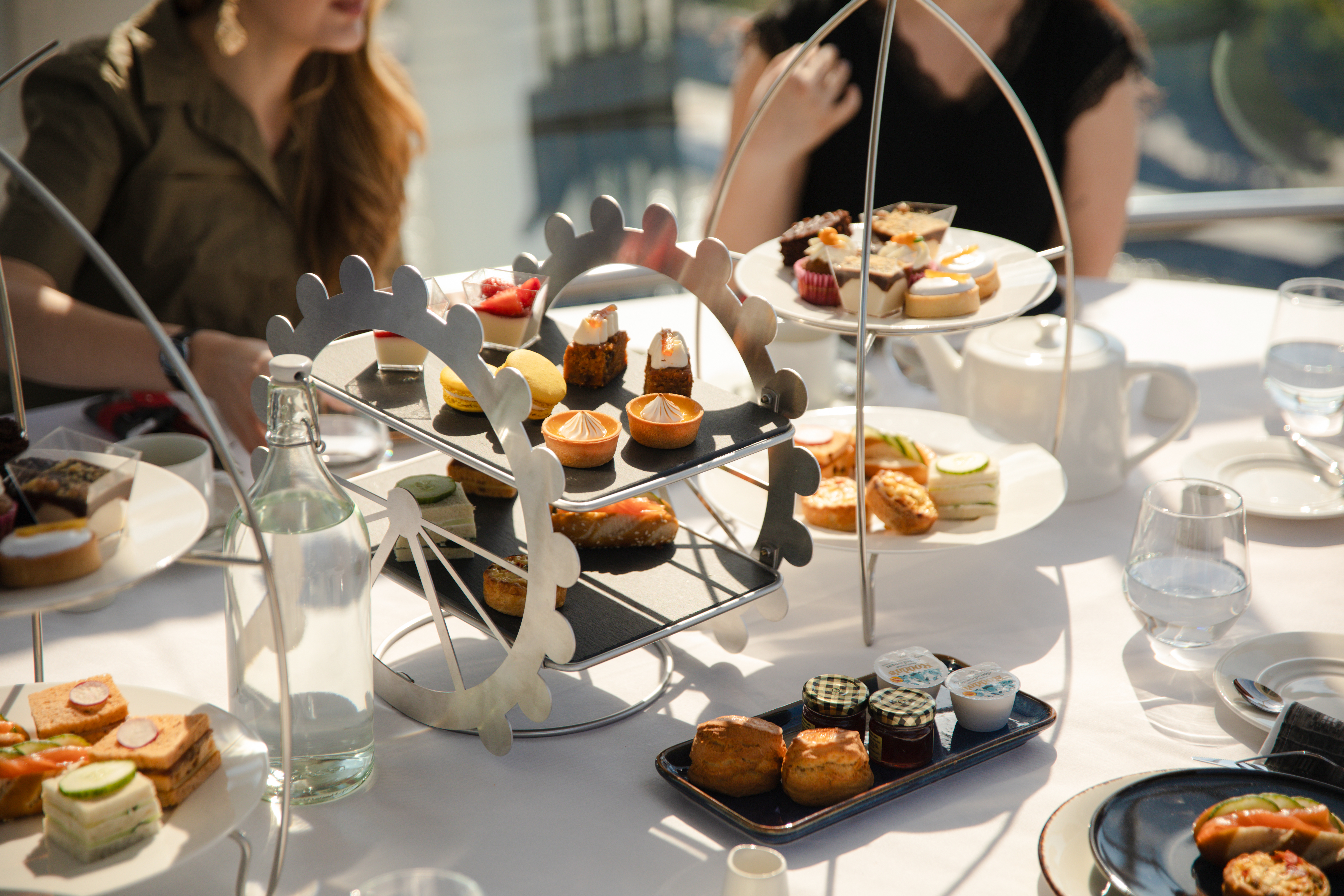 Afternoon tea setup with pastries and sandwiches on a London Eye-themed stand.