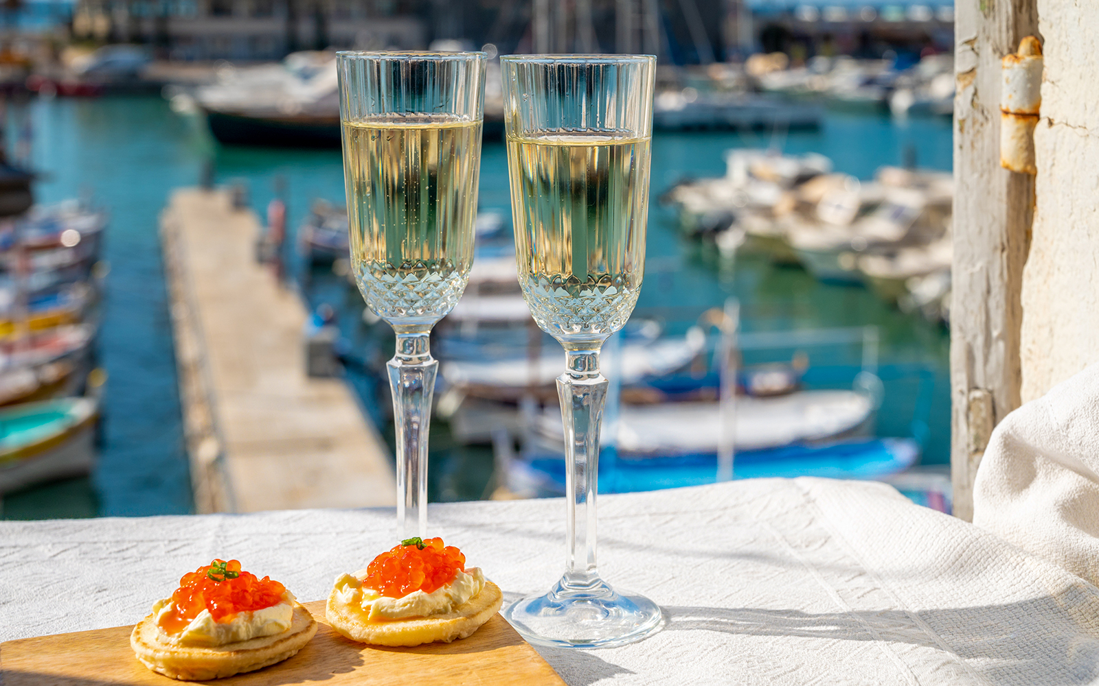 Champagne glasses and appetizers on a table overlooking boats on the Tiber River in Rome.