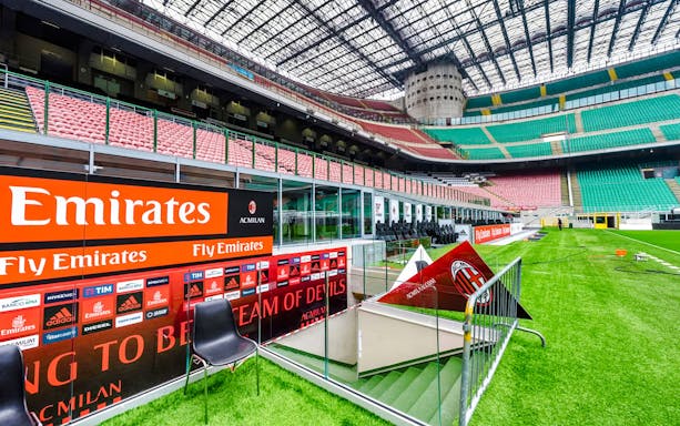 Players tunnel entrance at San Siro stadium with seating and advertising boards.