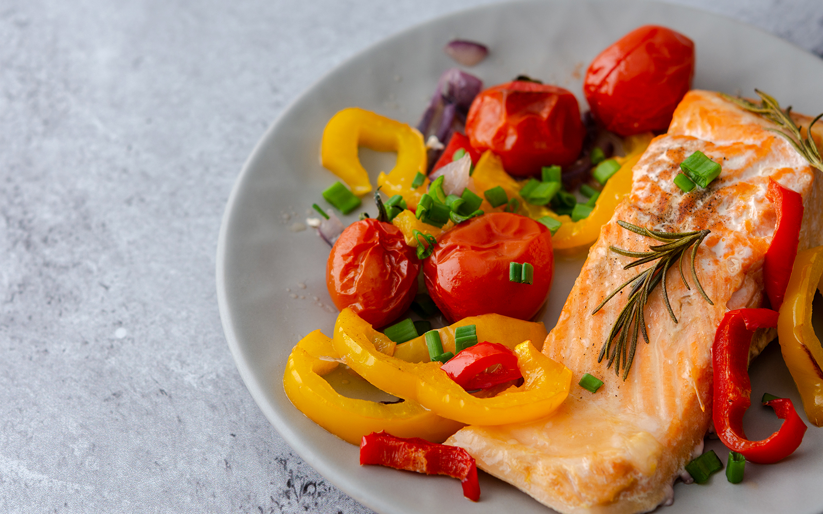 Arctic char fillet with cherry tomatoes and bell peppers on a plate.