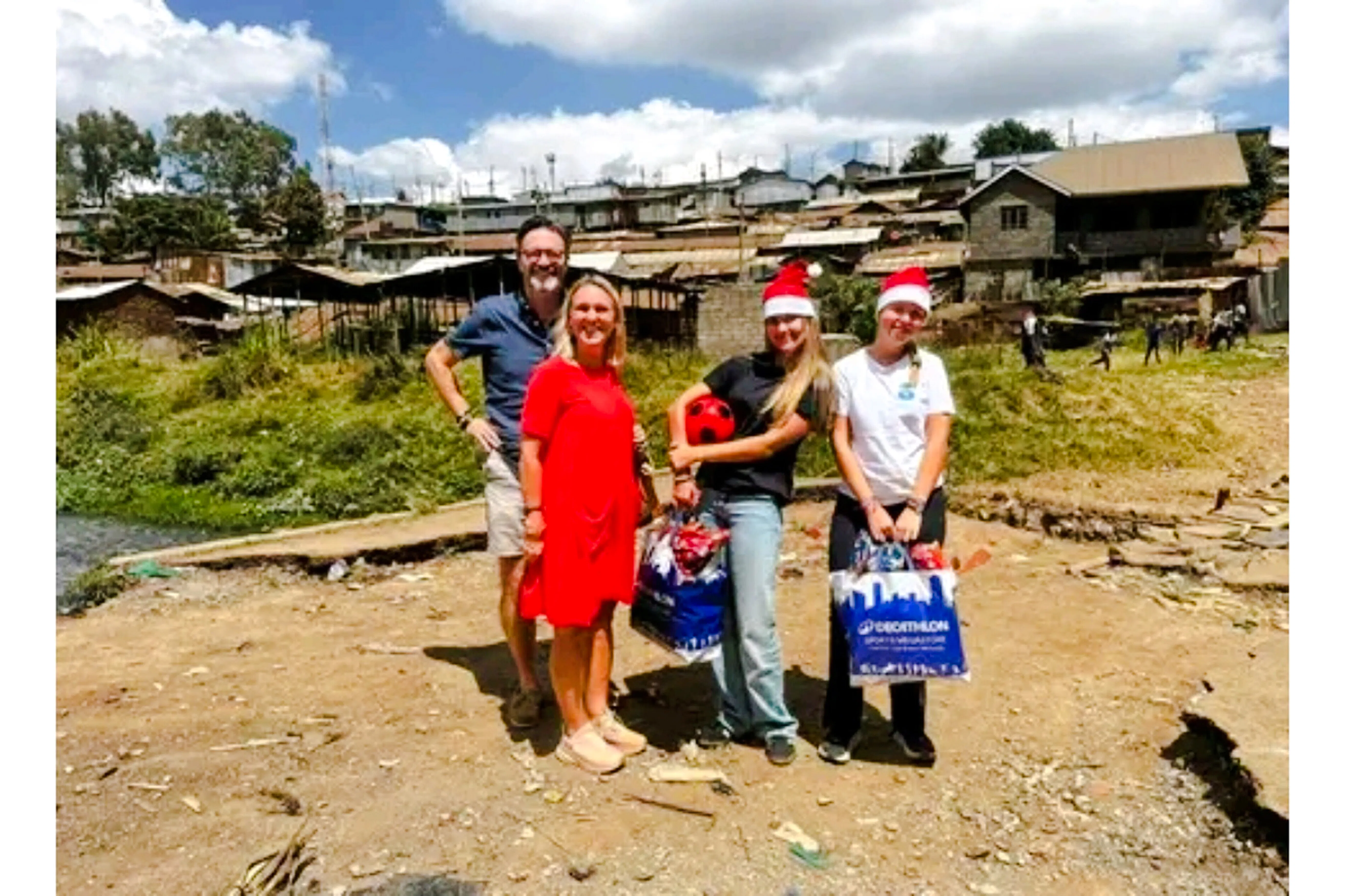 Group visiting Kibera Slum in Nairobi with gifts and festive hats.