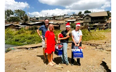 Group visiting Kibera Slum in Nairobi with gifts and festive hats.