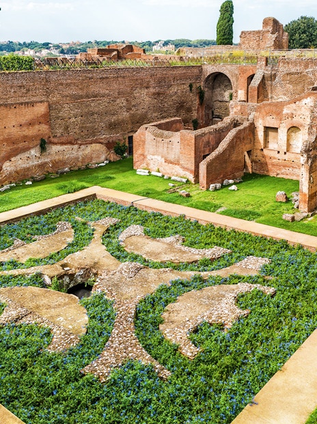 Roman Forum ruins with ancient brick walls and decorative garden, Palatine Hill, Rome.