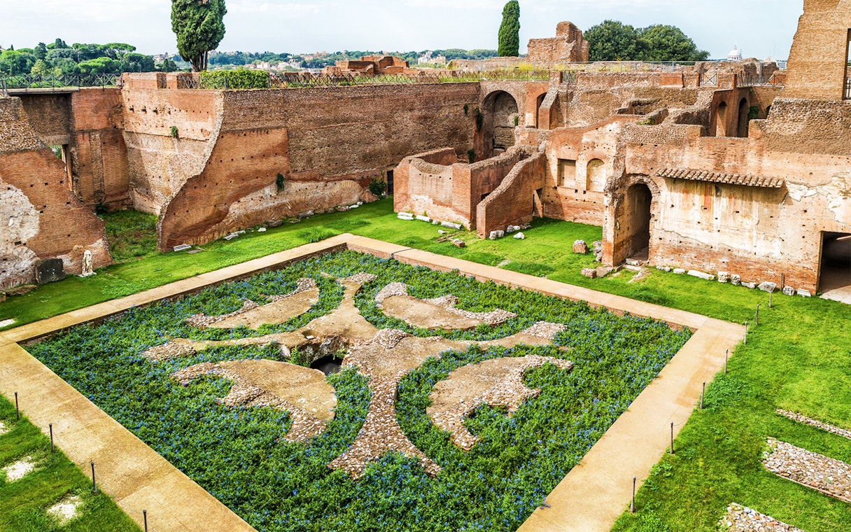 Roman Forum ruins with ancient brick walls and decorative garden, Palatine Hill, Rome.