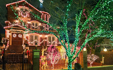 Christmas lights adorn a house and trees in Brooklyn on the New York Christmas Lights Bus Tour.