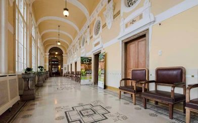 Hallway of Szechenyi Spa with ornate ceiling and seating area.