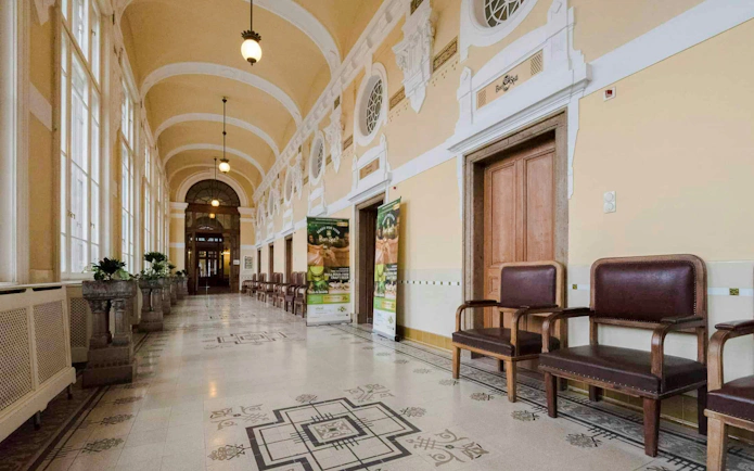 Hallway of Szechenyi Spa with ornate ceiling and seating area.