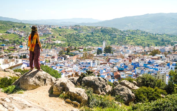 Traveler overlooking Chefchaouen, the blue city, from a hilltop in Morocco.