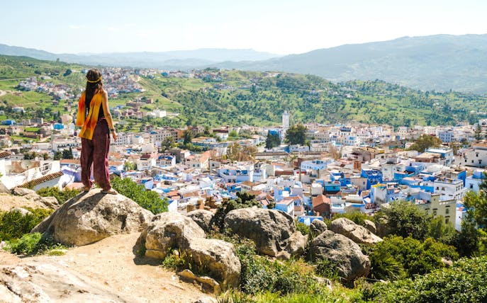 Traveler overlooking Chefchaouen, the blue city, from a hilltop in Morocco.