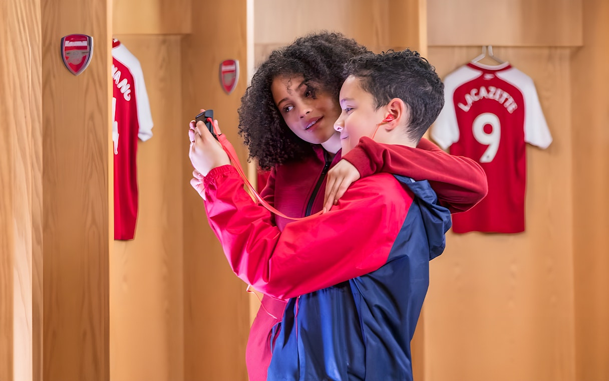 Children using audio guide in Arsenal FC Emirates Stadium locker room.