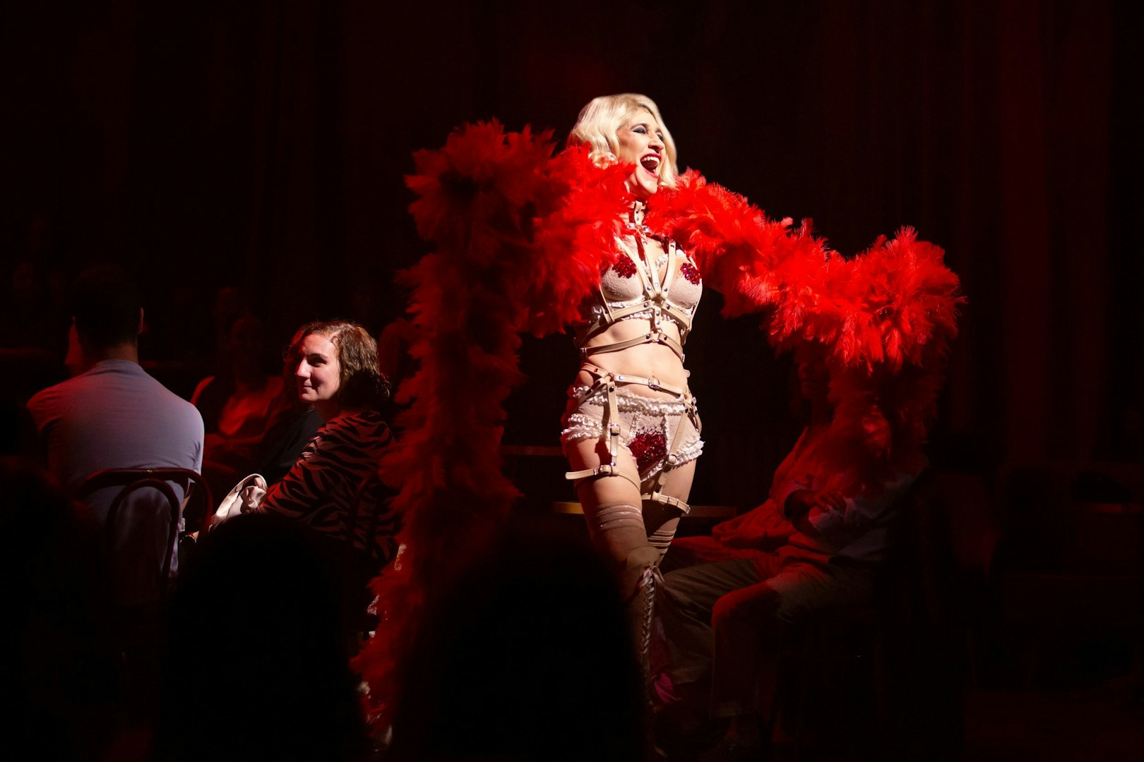 Performer with red feather boa on stage during Cabaret show in Madrid.