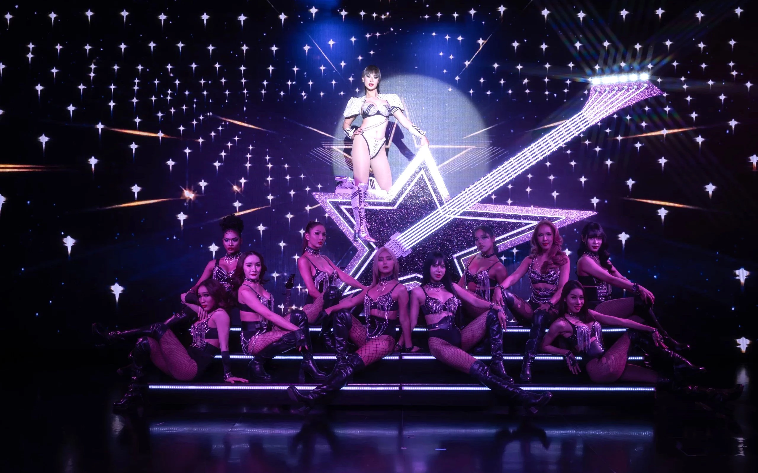 Performers on stage at Calypso Cabaret show in Bangkok with starry backdrop.