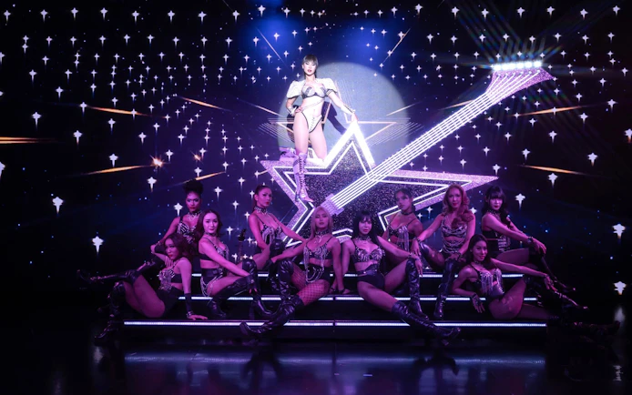 Performers on stage at Calypso Cabaret show in Bangkok with starry backdrop.