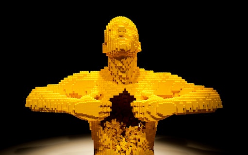 Yellow LEGO sculpture of a human figure opening its chest, featured in Australia: The Art of the Brick.