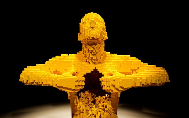 Yellow LEGO sculpture of a human figure opening its chest, featured in Australia: The Art of the Brick.