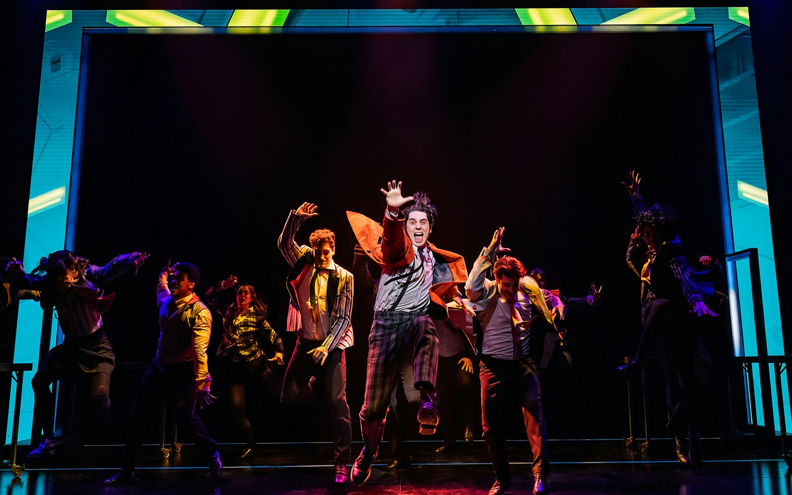 Performers energetically dancing on stage during The Who’s Tommy musical.