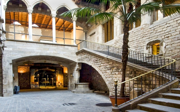 Exterior courtyard of Picasso Museum, Barcelona, featuring stone arches and a staircase.