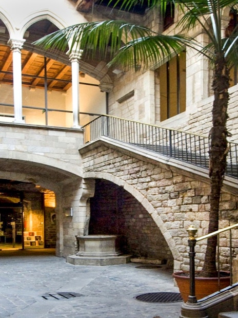 Exterior courtyard of Picasso Museum, Barcelona, featuring stone arches and a staircase.
