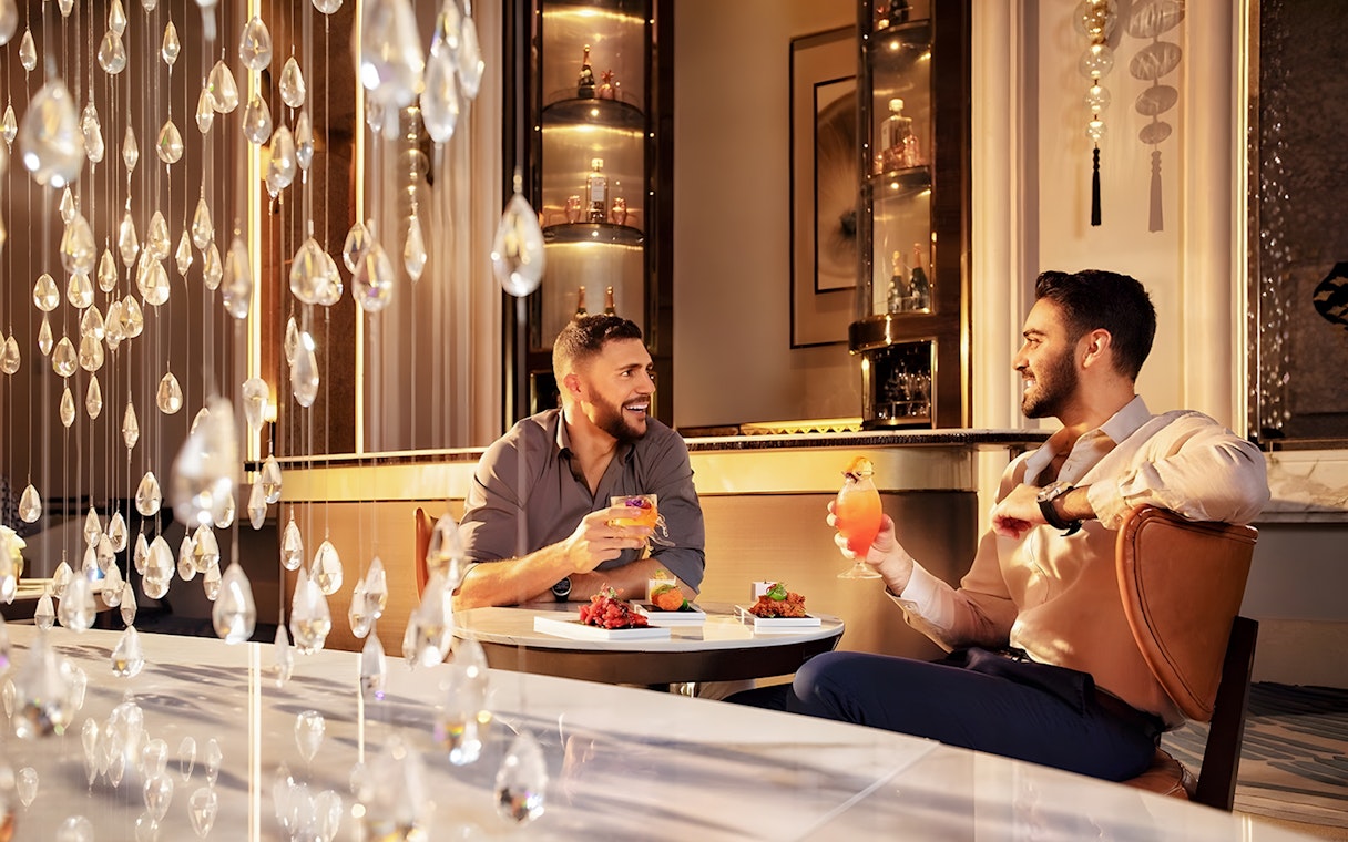 Men enjoying signature cocktails with cake at Pearl Afternoon Tea, Platos.
