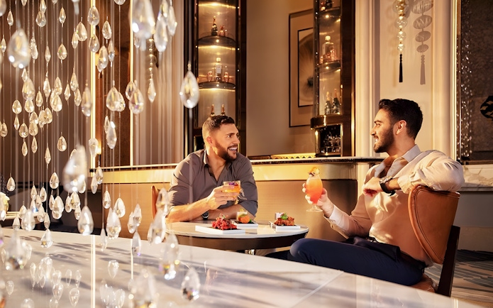 Men enjoying signature cocktails with cake at Pearl Afternoon Tea, Platos.