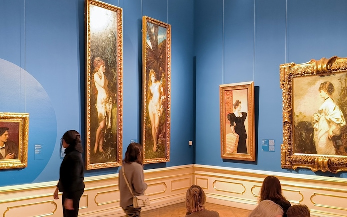 Visitors viewing paintings on a guided tour at Upper Belvedere Palace art gallery.