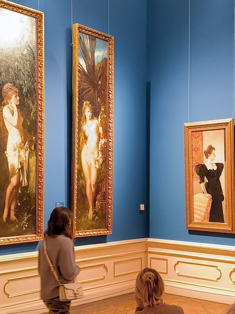 Visitors viewing paintings on a guided tour at Upper Belvedere Palace art gallery.