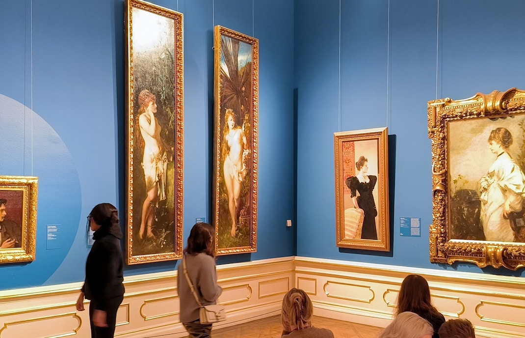 Visitors viewing paintings on a guided tour at Upper Belvedere Palace art gallery.