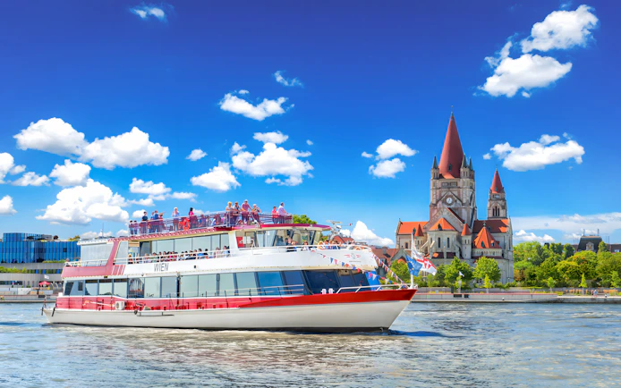 MS Wien ship cruising on the Danube River with St. Francis of Assisi Church in Vienna, Austria.