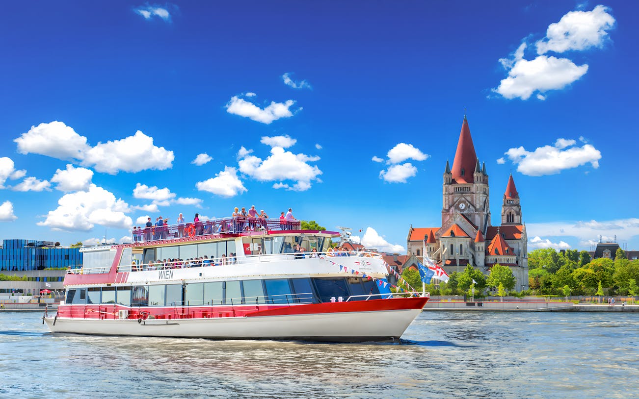 MS Wien ship cruising on the Danube River with St. Francis of Assisi Church in Vienna, Austria.