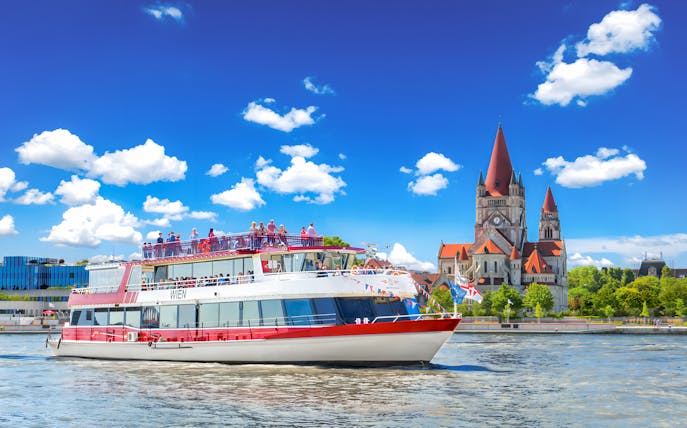 MS Wien ship cruising on the Danube River with St. Francis of Assisi Church in Vienna, Austria.
