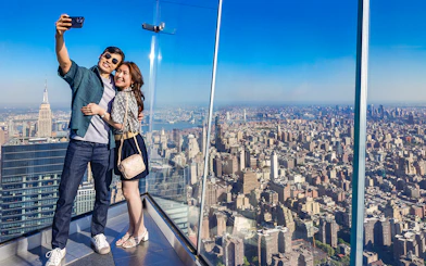Couple taking a selfie at Edge Observation Deck with New York City skyline.