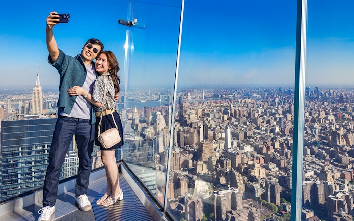 Couple taking a selfie at Edge Observation Deck with New York City skyline.