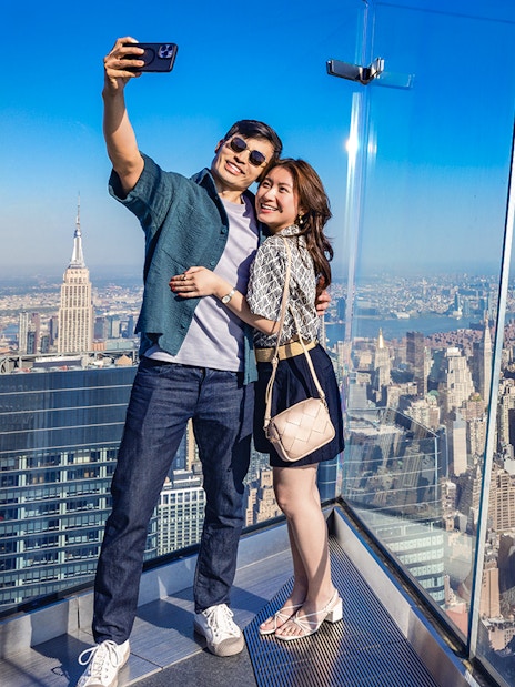 Couple taking a selfie at Edge Observation Deck with New York City skyline.