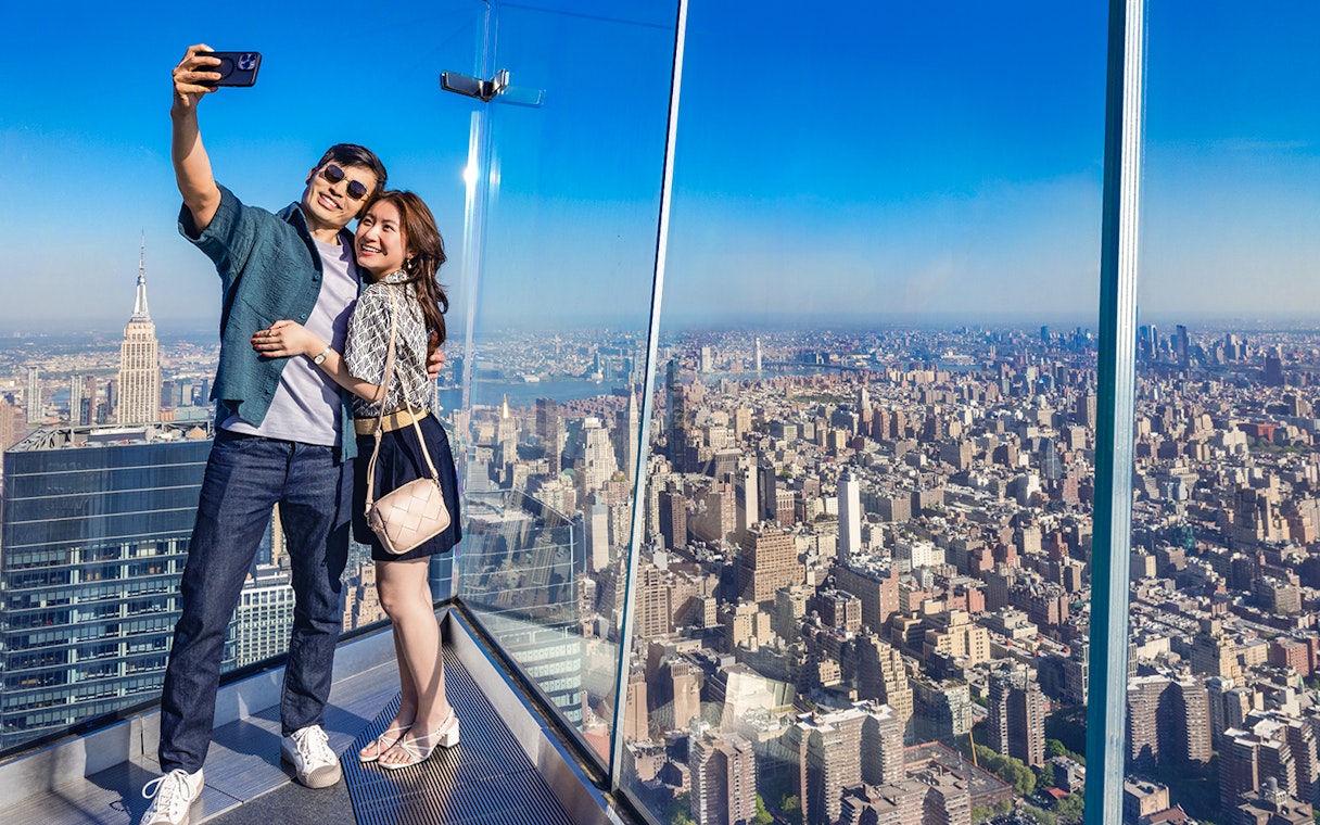 Couple taking a selfie at Edge Observation Deck with New York City skyline.