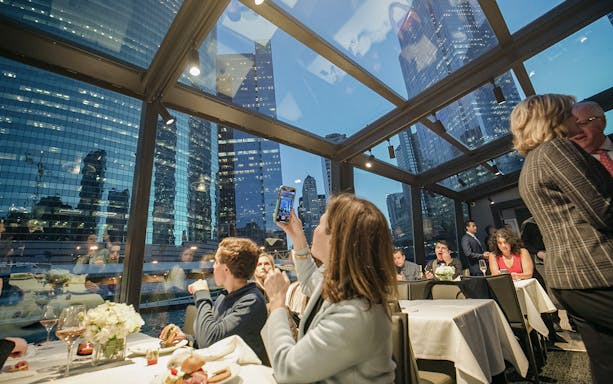 Guests dining on Chicago Premier Plus Dinner Cruise with city skyline views.