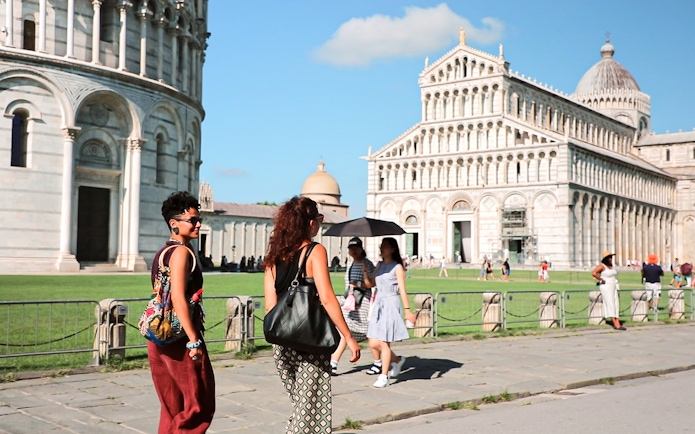 Tourists walking near Pisa Cathedral on a guided tour from Florence.